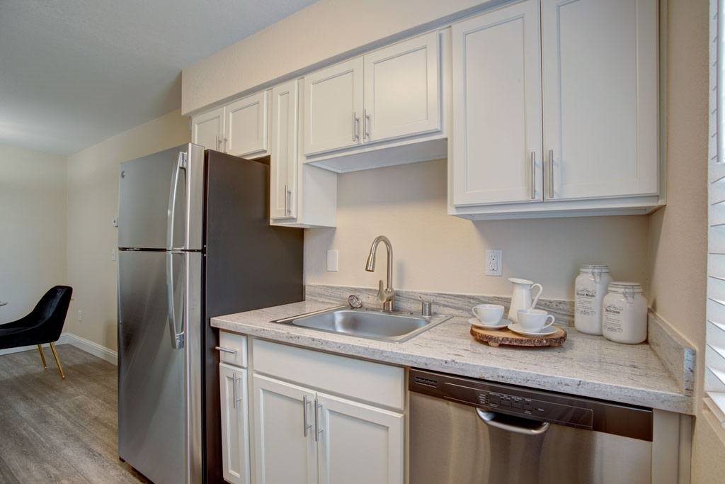 A kitchen with white cabinets and a stainless steel refrigerator.